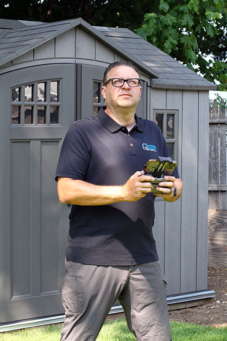inspector in yard holding drone controller looking toward sky